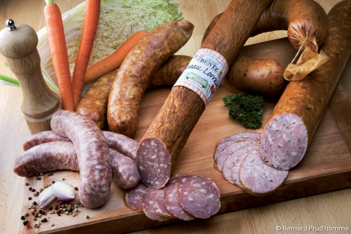 Sélection de charcuterie de la maison Bentz : saucisse fumée entourée de carottes et pommes de terre.