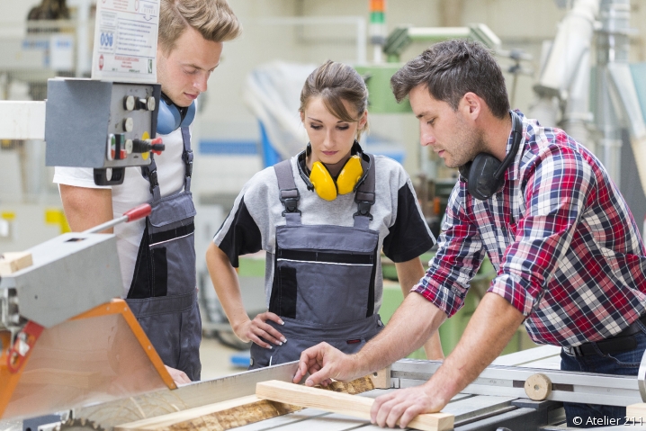 apprentis Apprentis en menuiserie autour d'un établi écoutant leur maître d'apprentissage