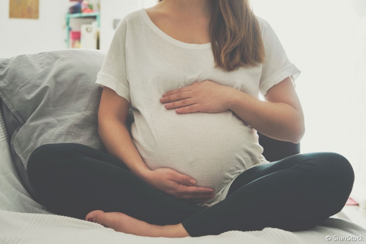 Femme enceinte assise en tailleur et touchant son ventre
