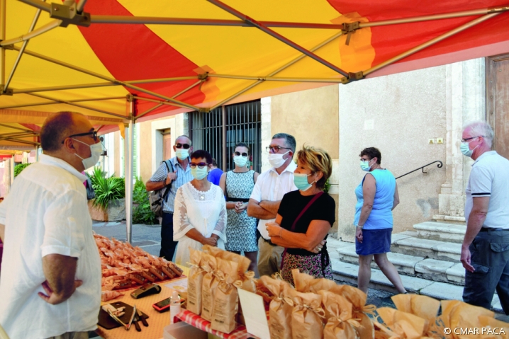 Un producteur échange avec les visiteurs d'un marché