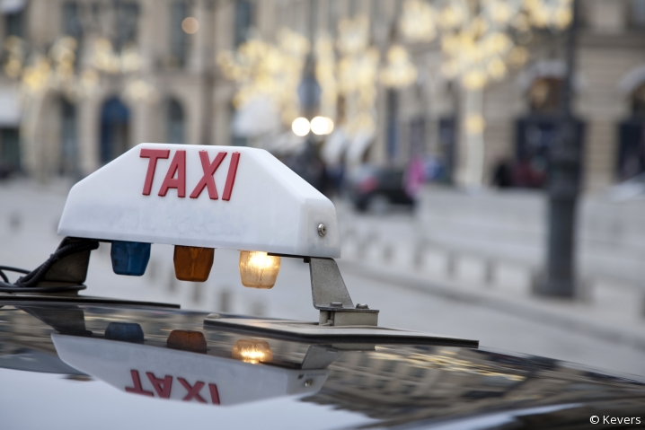 Gros plan sur le panneau blanc lumineux "taxi" qui surmonte les voitures à Paris