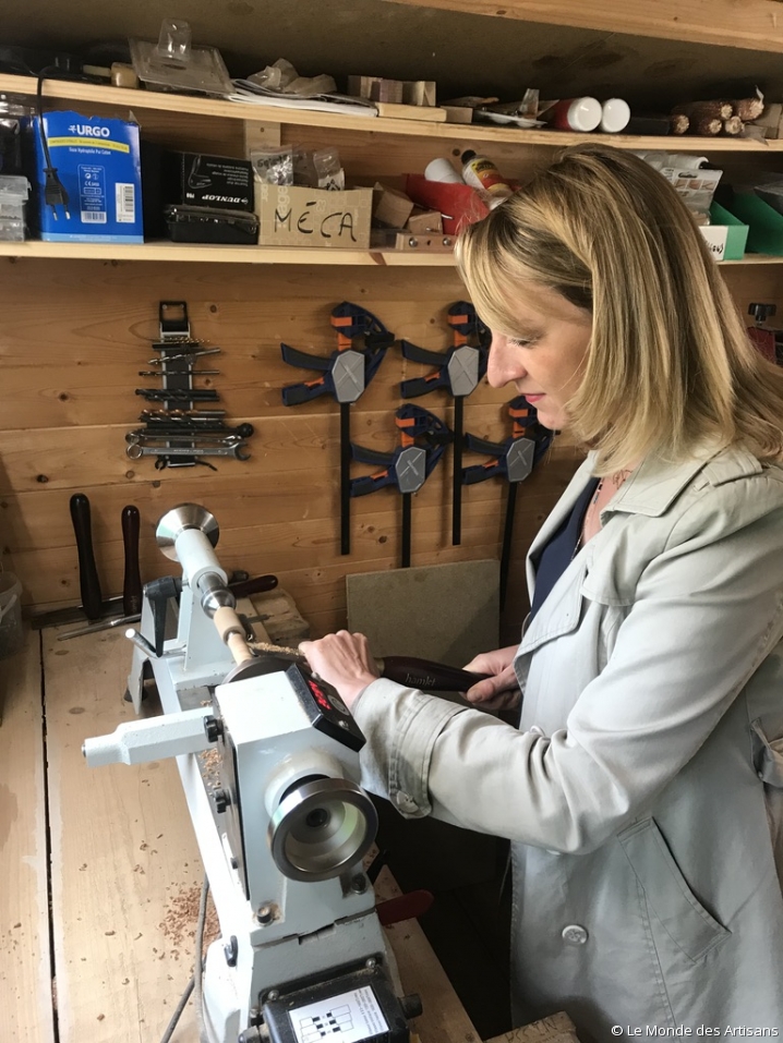 Vêtue d'une blouse blanche, la journaliste Julie Clessienne s'essaie au tour de bois