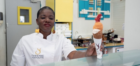 L'artisan guadeloupéenne Fabienne Youyoutte tenant une glace dans sa boutique