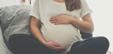 Femme enceinte assise en tailleur et touchant son ventre