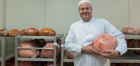 Jean-François Antoine pose avec un de ses jambons dans un atelier de la Charcuterie Bentz