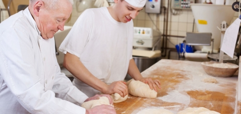 Artisan boulanger pétrissant des pâtons aux côtés de son apprenti