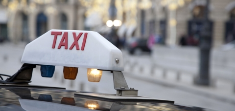 Gros plan sur le panneau blanc lumineux "taxi" qui surmonte les voitures à Paris